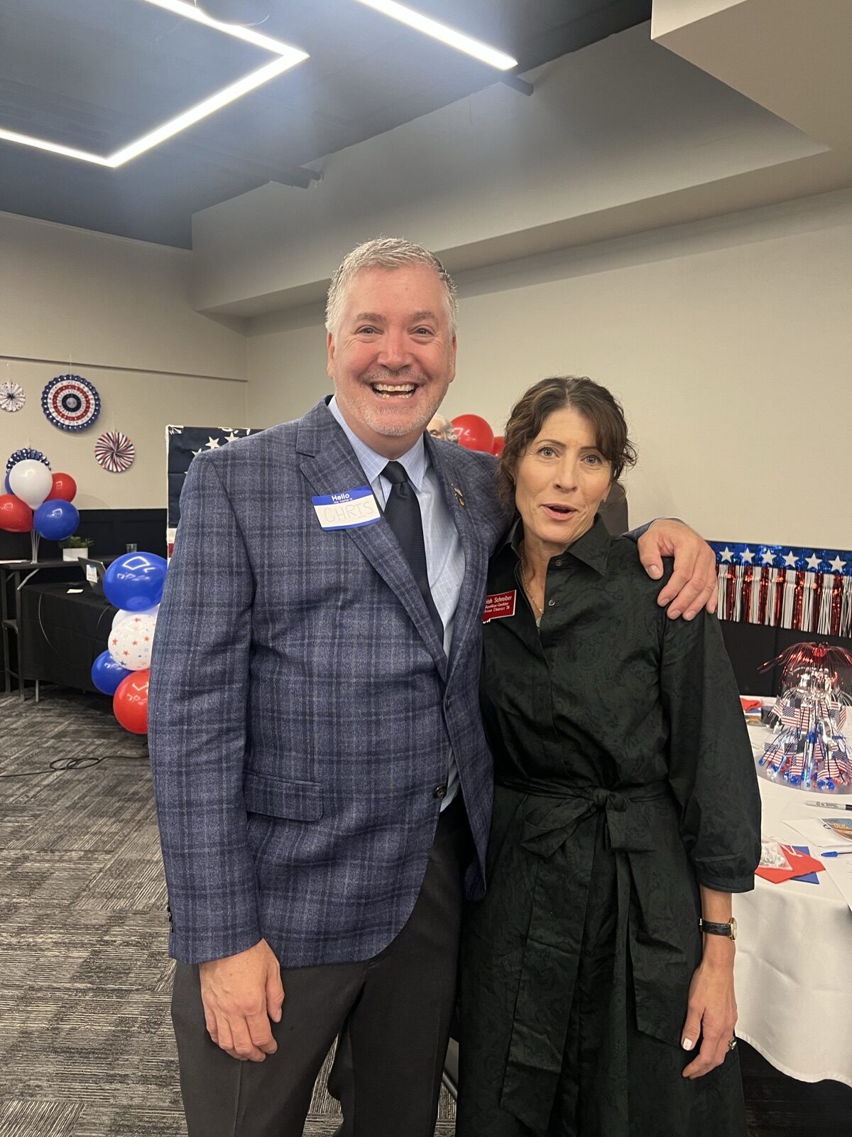 Emcee Chris Warden stands with a guest in front of patriotic balloons at Celebrate America.