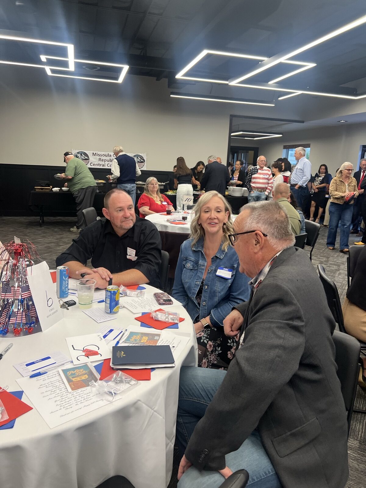 Guests visit around a decorated table as the Celebrate America dining room fills.
